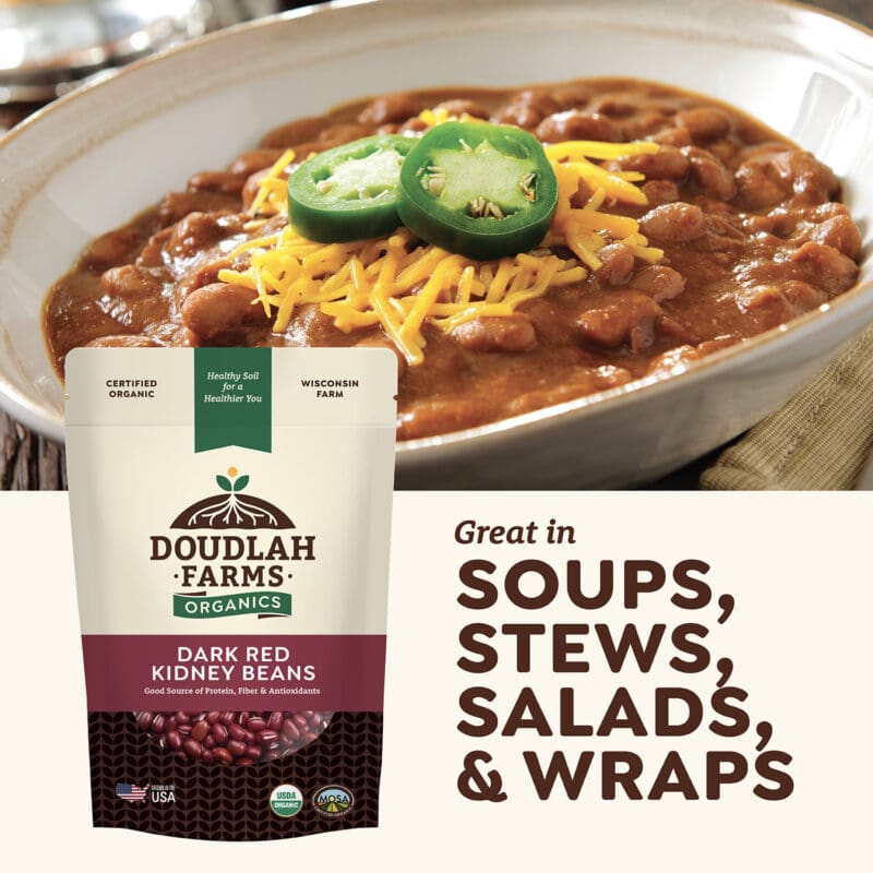 A bowl of chili garnished with jalapeño slices and shredded cheese highlights Kidney Beans from Doudlah Farms Organics. Text reads: Ideal for soups, stews, salads, and wraps.