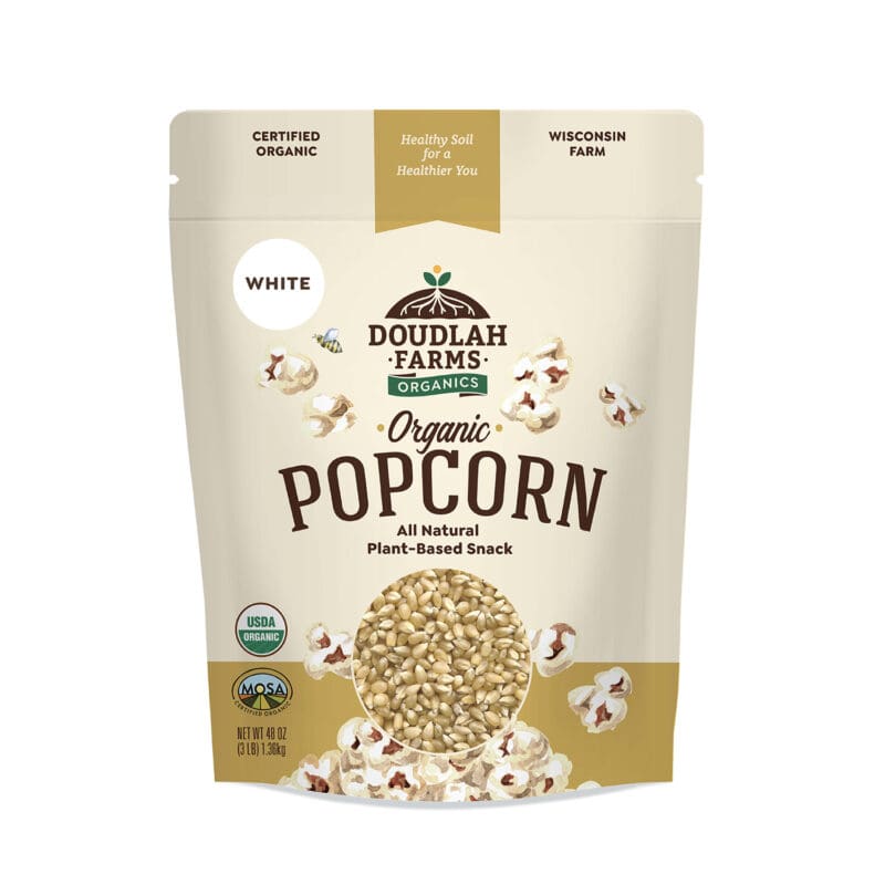 A beige bag of Doudlah Farms Organics white popcorn. The packaging, adorned with popcorn kernels and popped corn accents, highlights its 3LB size. Labels confirm it's certified organic, plant-based, and from Wisconsin. USDA Organic and MOSA Certified logos are prominently visible.