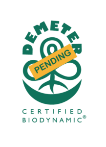 Demeter Certified Biodynamic logo with the word Pending across it. The design features a stylized plant emblem in green and yellow.