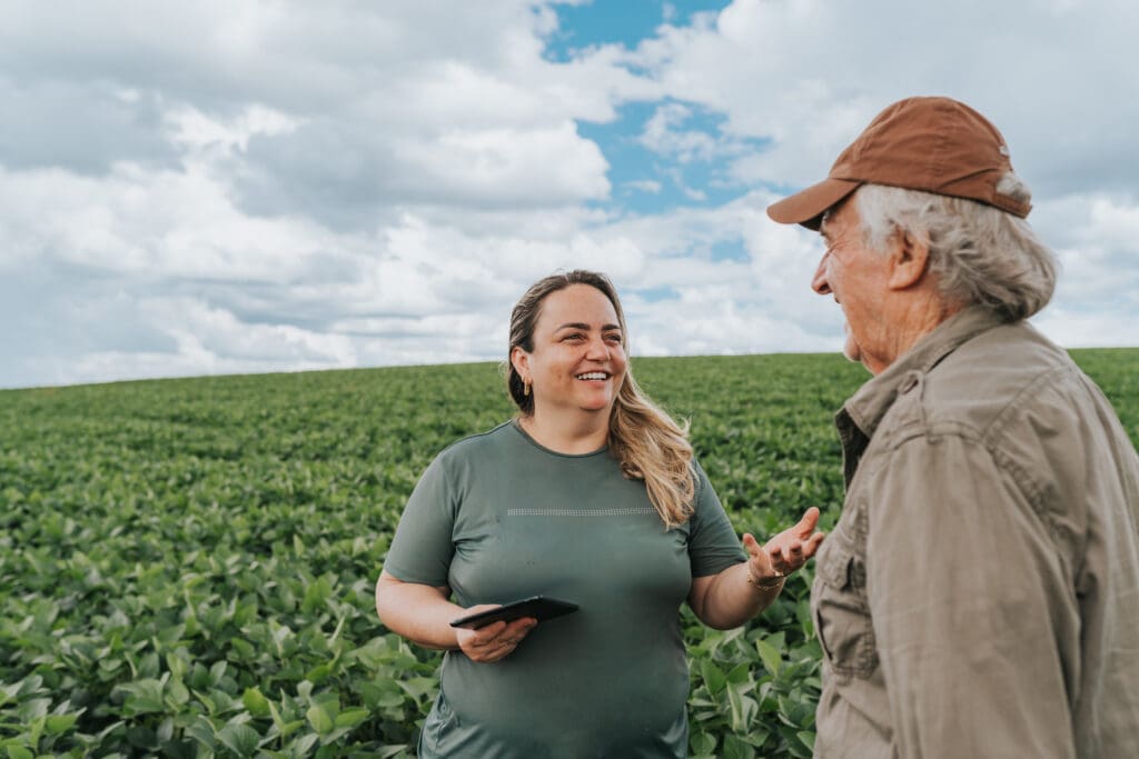 A farmer and a consumer having a friendly conversation in a lush green field, highlighting the connection between family farms and their communities.