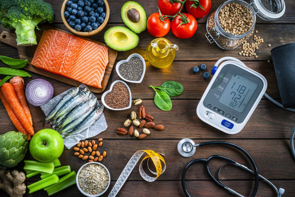 A heart-healthy diet with fresh salmon, nuts, vegetables, and legumes, alongside a blood pressure monitor, promoting nutrition for cardiovascular wellness.