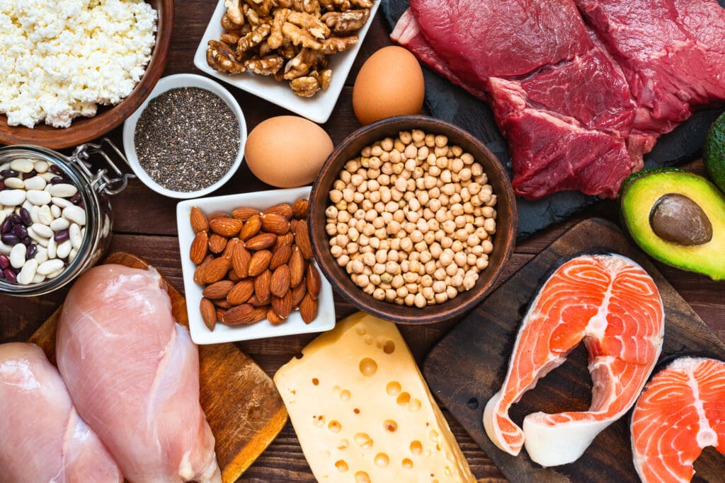 A variety of protein-rich foods, including beans, nuts, eggs, chicken, salmon, and avocado, showcasing essential nutrients for heart health, digestion, and weight management.