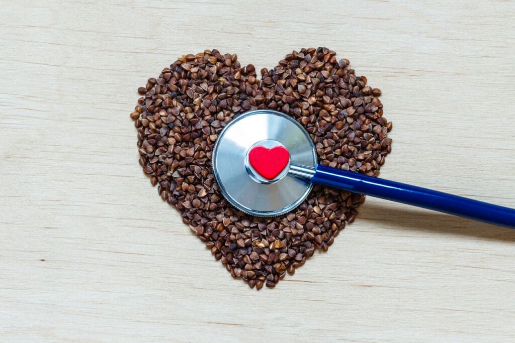 A heart-shaped arrangement of buckwheat groats with a stethoscope, symbolizing the heart-health benefits of buckwheat and its role in cardiovascular wellness.