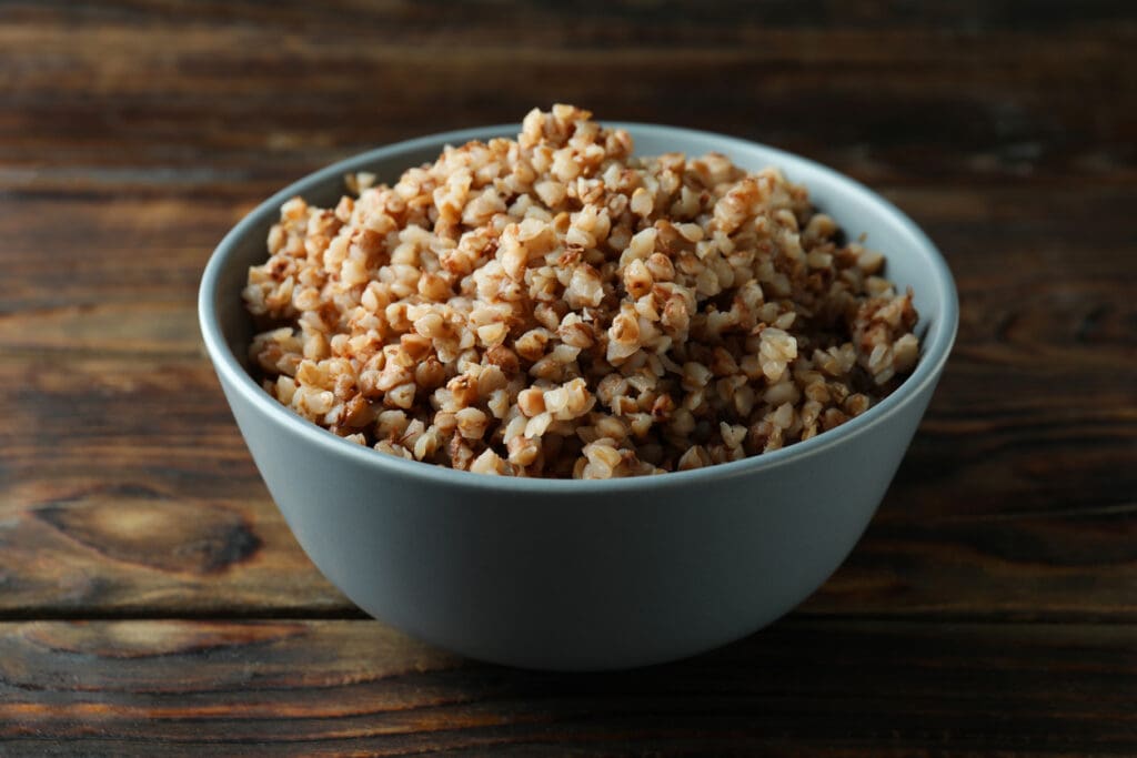 A bowl of cooked buckwheat groats on a rustic wooden table, showcasing a gluten-free, nutrient-dense whole grain rich in fiber, antioxidants, and plant-based protein.