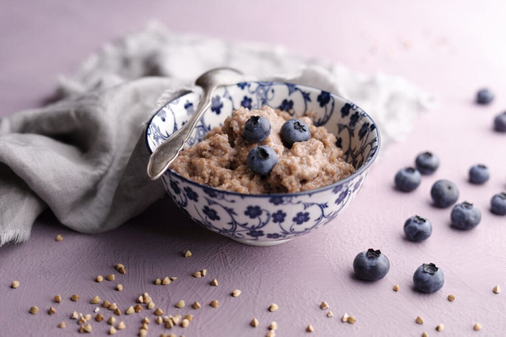 A bowl of creamy buckwheat porridge topped with fresh blueberries, a delicious gluten-free breakfast rich in fiber and plant-based protein.