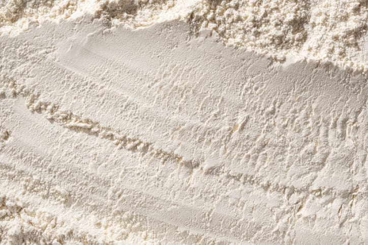 Close-up of a smooth, even layer of organic flour with visible texture and ridges created by something being dragged across the surface.